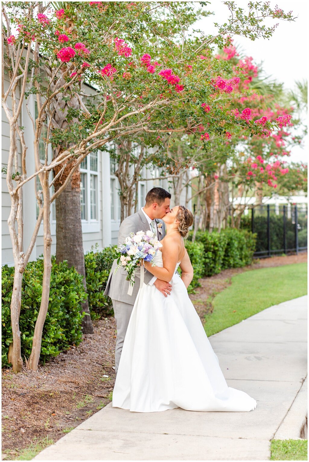 bride and groom standing under pink tree  kissing