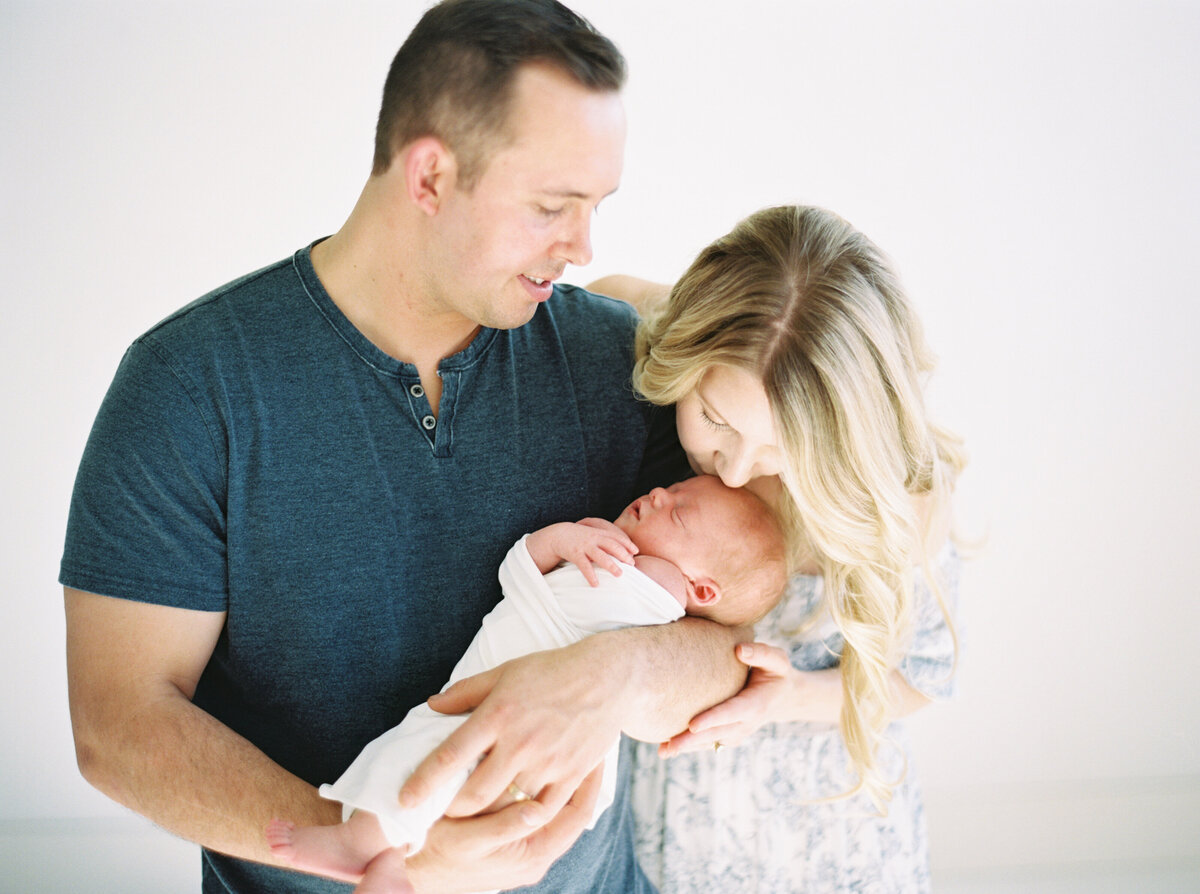 couple in light blue outfits holding newborn baby taken by photographer milwaukee wi Talia Laird Photography