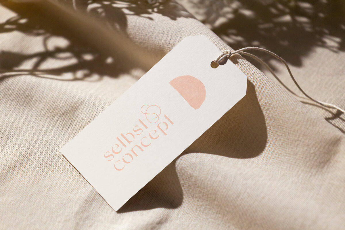 Hang tag with feminine, sophisticated branding laying on a linen cloth