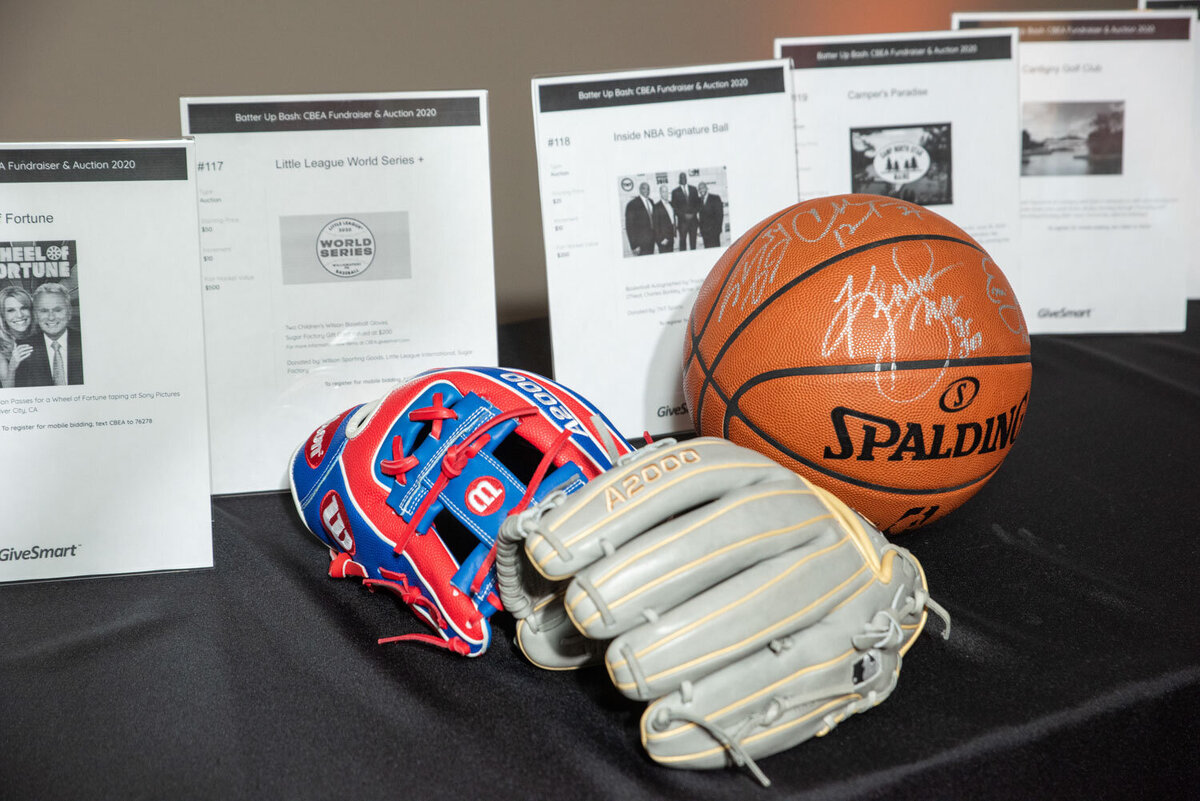 Baseball gloves and a signed basketball on display at a silent auction