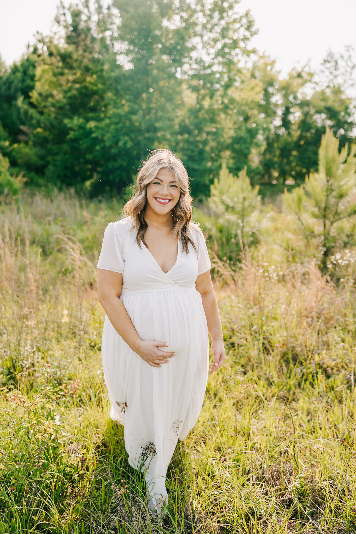 Pregnant mom wearing a white dress during her maternity session in an open field in Evans, georgia.