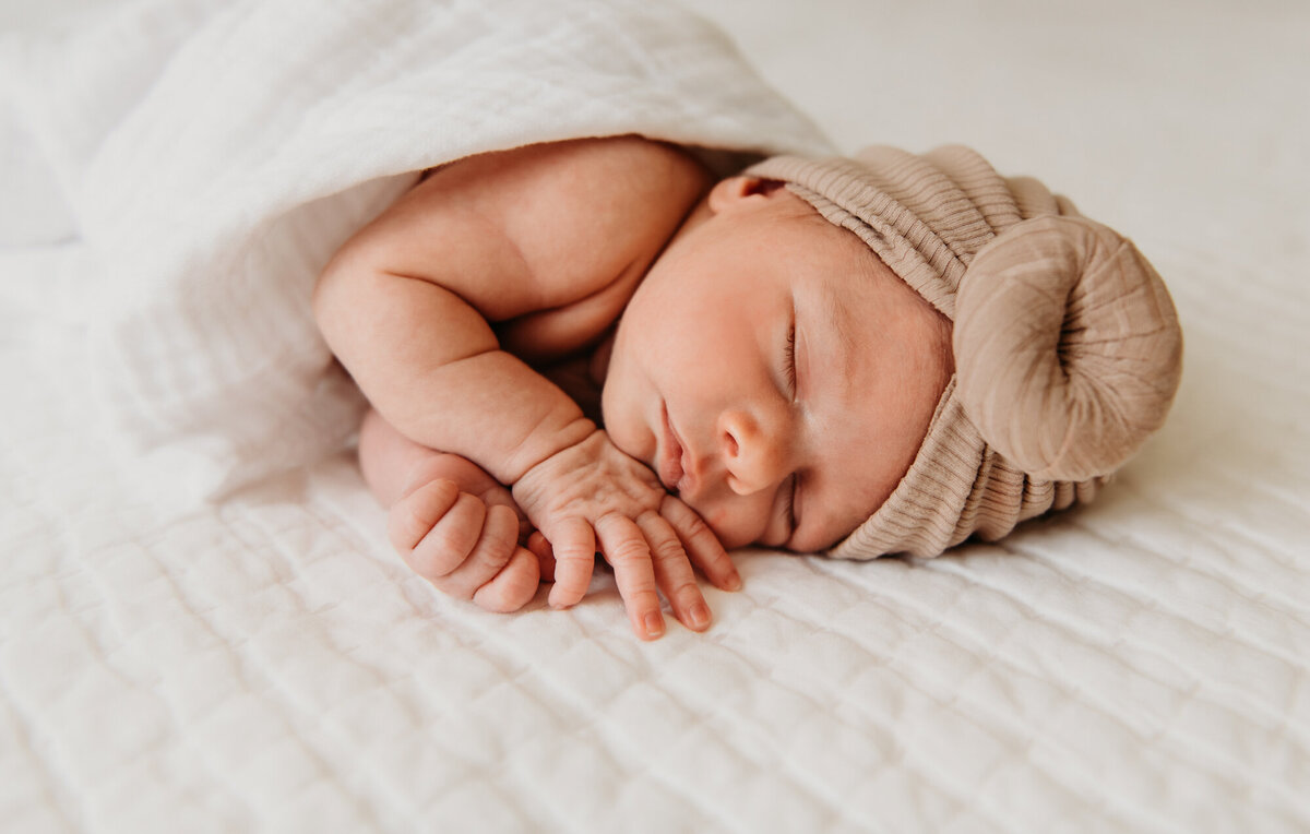 Newborn Photography, Baby girl sleeping on her belly wrapped in a blanket on the bed.