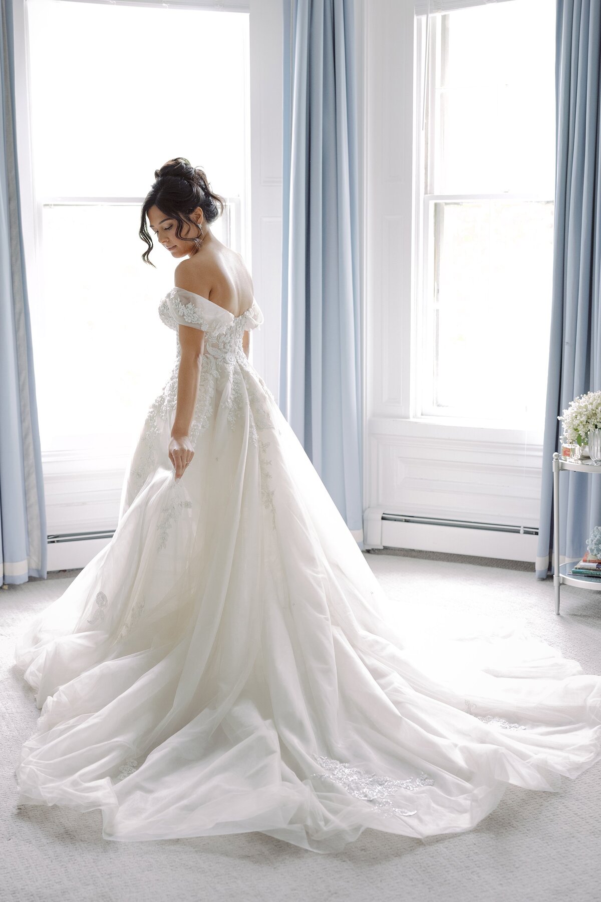 Bride looks over shoulder as she gets into her wedding dress during wedding in Newport.
