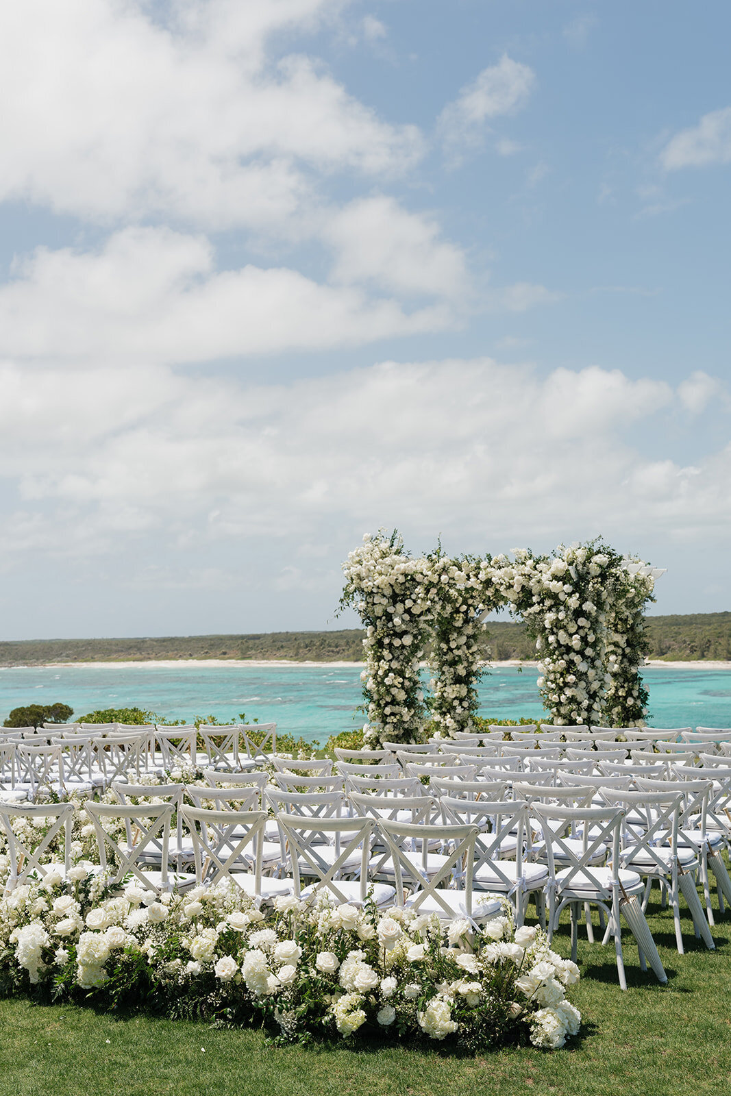 Bahamas Island wedding ceremony. Wedding flowers for island wedding in white and green tones. Epic wedding ceremony on oceanside cliff. Destination wedding floral design by Rosemary & Finch Floral Design in Nashville, TN.