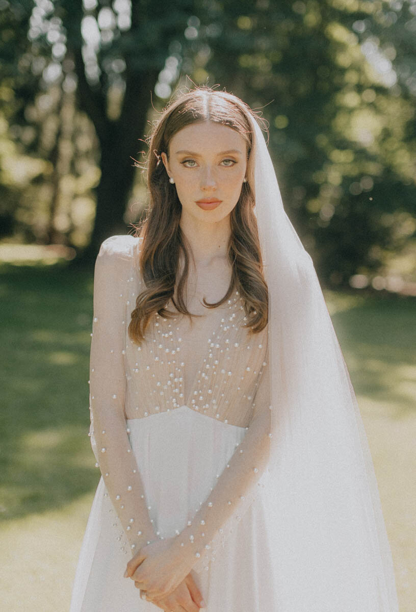 bride standing holding her hand and looking at the camera