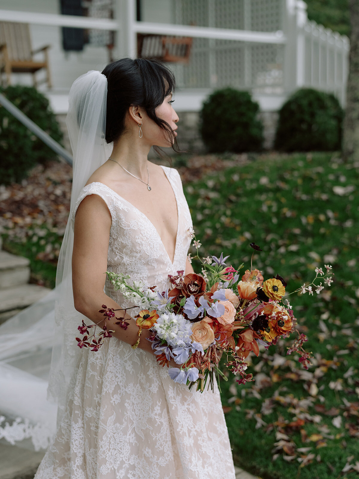 Organic artistic bridal bouquet with delicate blooms and texture. Fall bridal bouquet for private home wedding featuring orchids, ranunculus, and sweet peas. Textural bridal bouquet in a tasteful fall pallet of copper, lavender, gold, and ruby. Private property autumnal wedding in the hills of Tennessee. Design by Rosemary & Finch Floral Design in Nashville, TN.