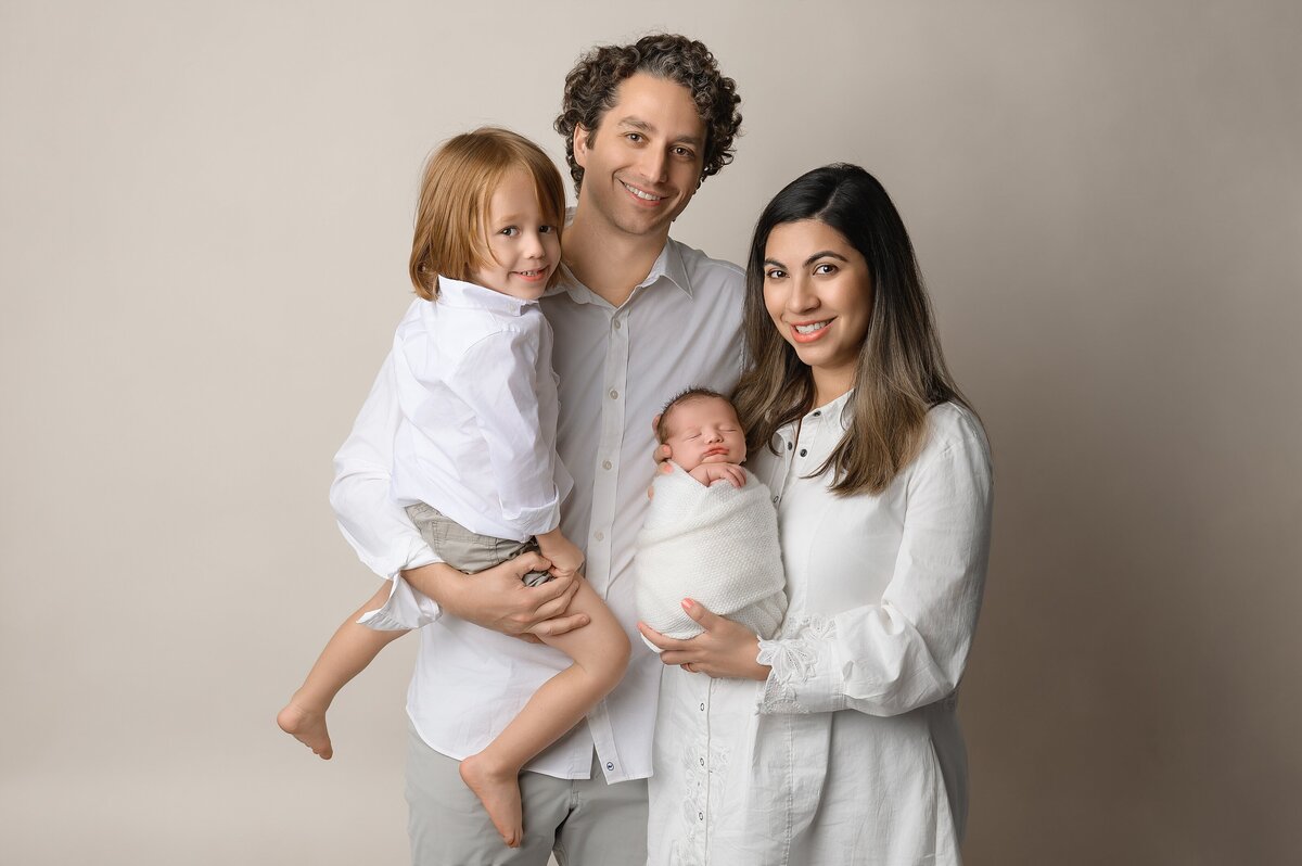 First family portrait with newborn sibling in professional photography studio.