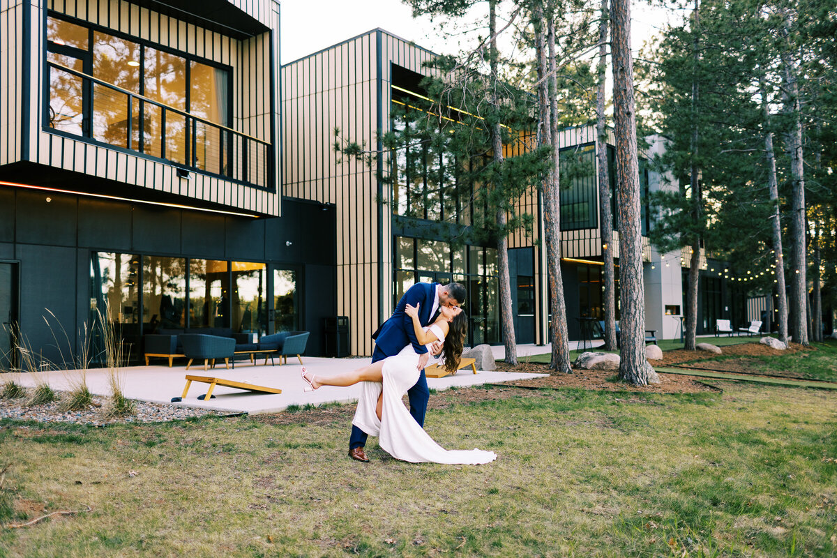 Groom is dipping and kissing his bride outside the Catalyst by Nature Link venue