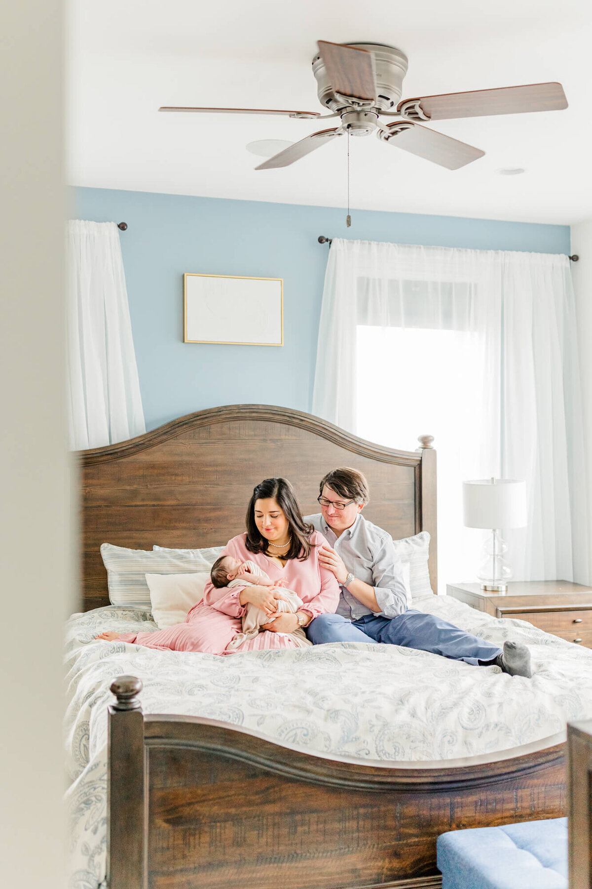 A mom and dad sit on their bed and admire their newborn in their Boston home