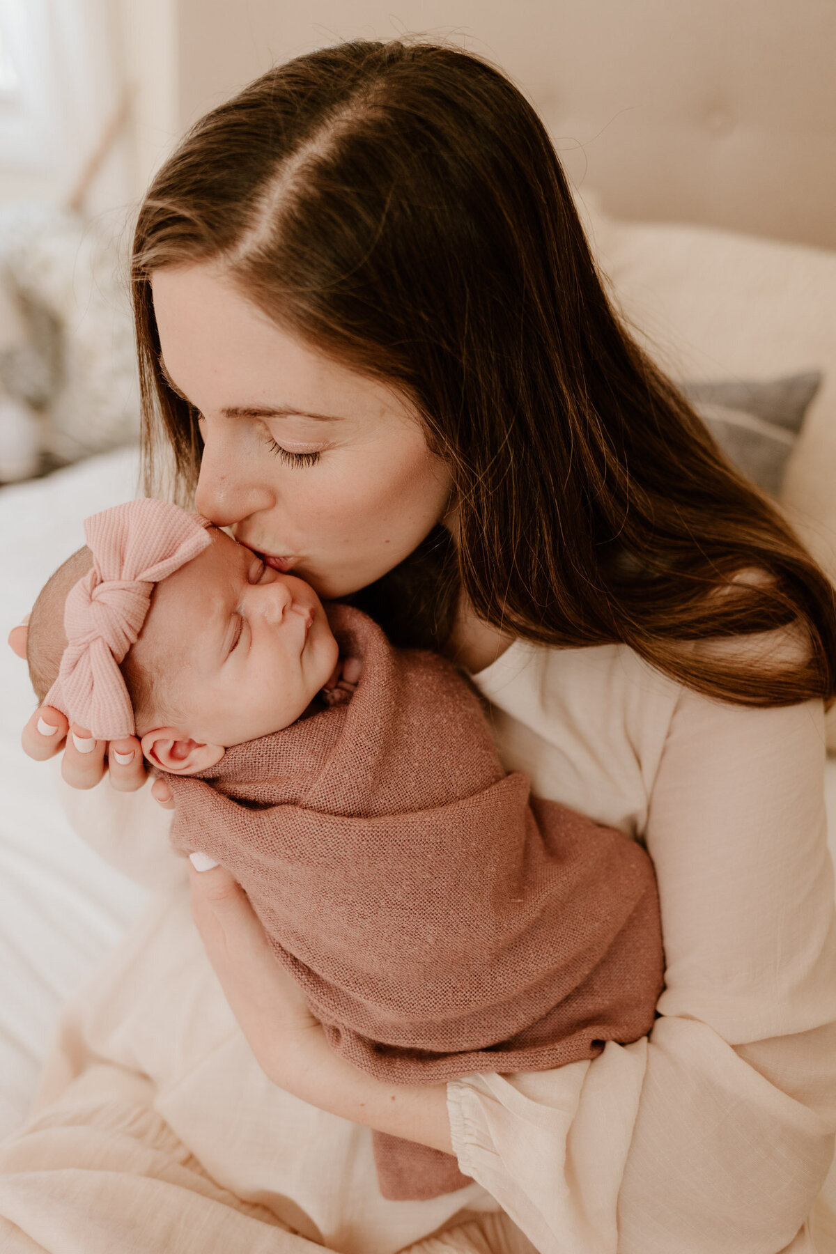 Loving mother kissing her baby’s forehead during a newborn photo session in Hudson Valley.