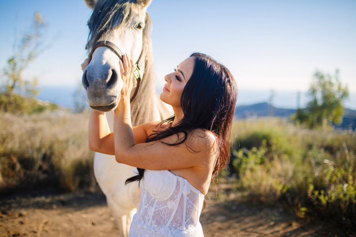 The bride pets a horse on her elopement day