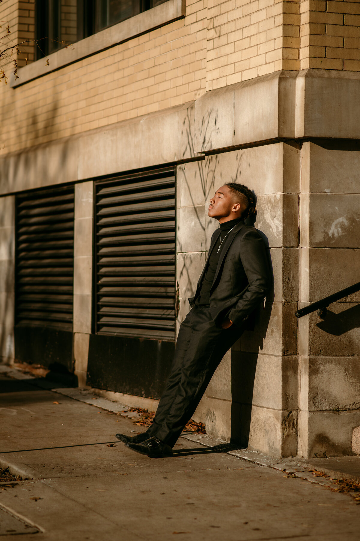 North high school male leaning up against a wall in lowertown St. Paul in the sunlight