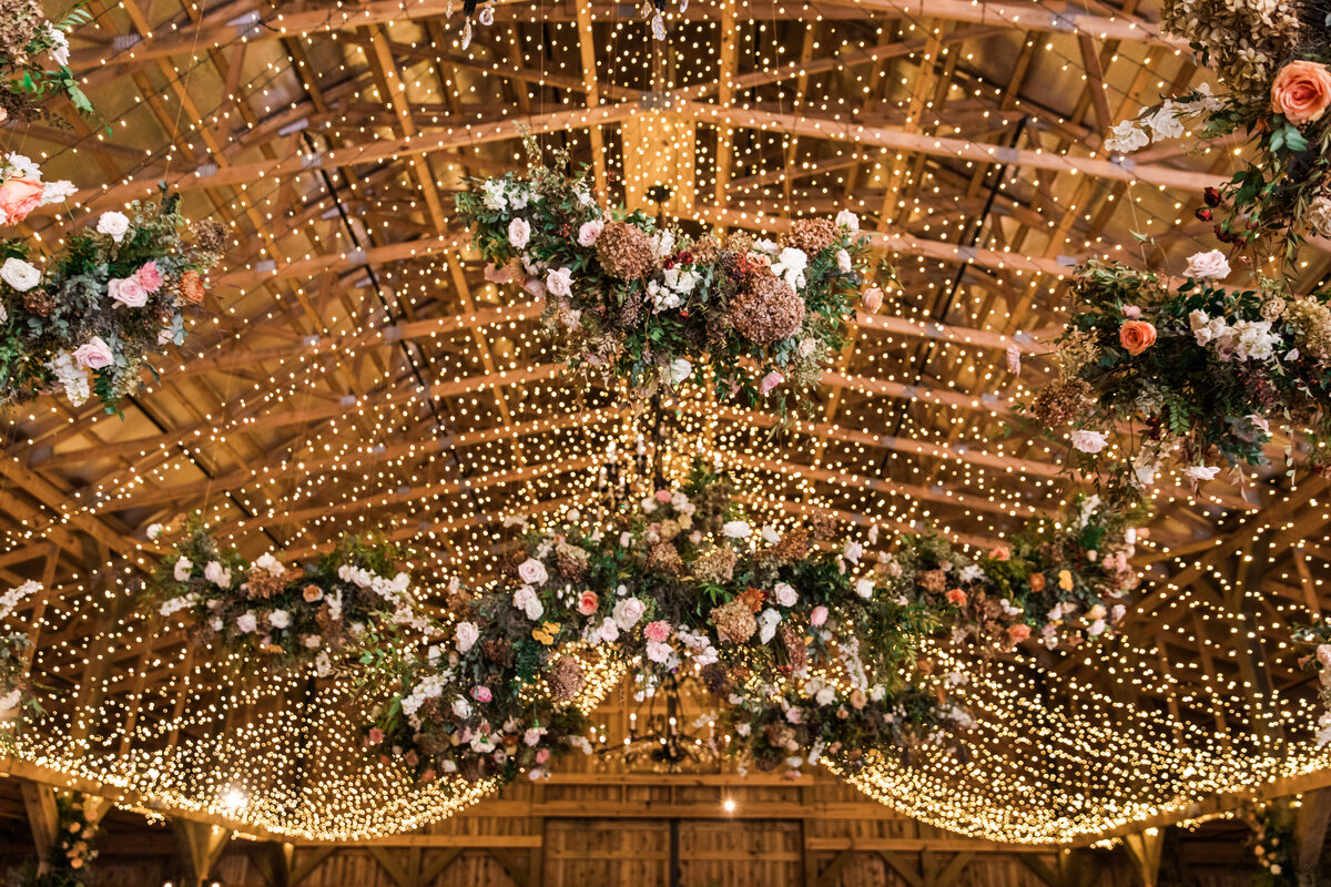 Gorgeous autumnal floral clouds hang over the dance floor, including terra cotta, rose gold, toffee, blush, and neutral florals. These clouds feature lush garden roses, ranunculus, lisianthus, and privet berries. Designed by Rosemary and Finch in Nashville, TN.