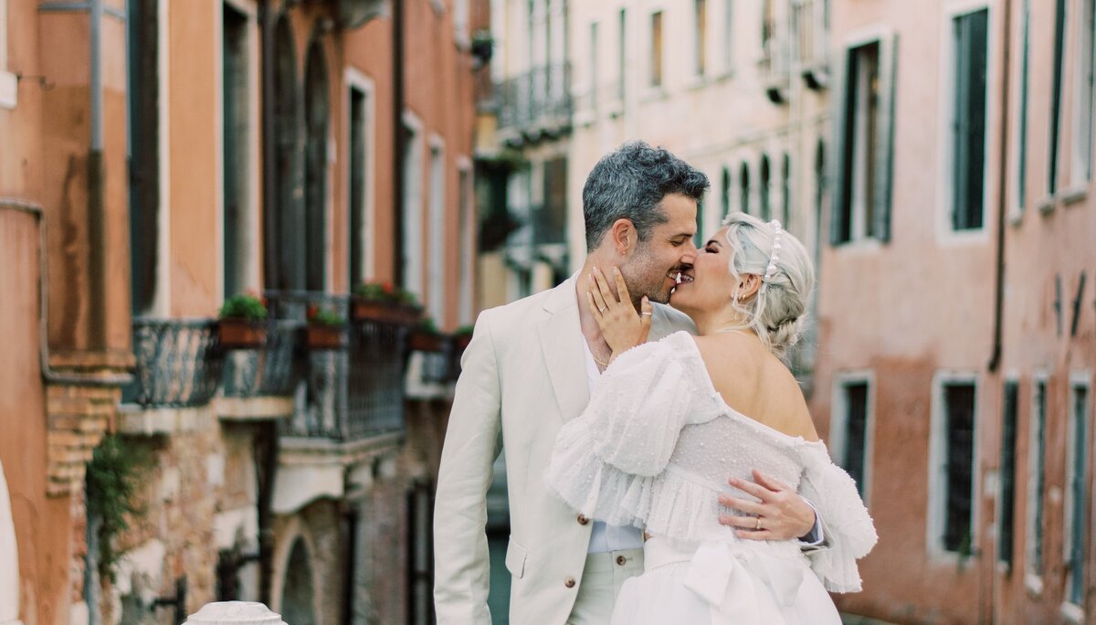 Bride and groom share a romantic moment on a quiet street in Venice, Italy