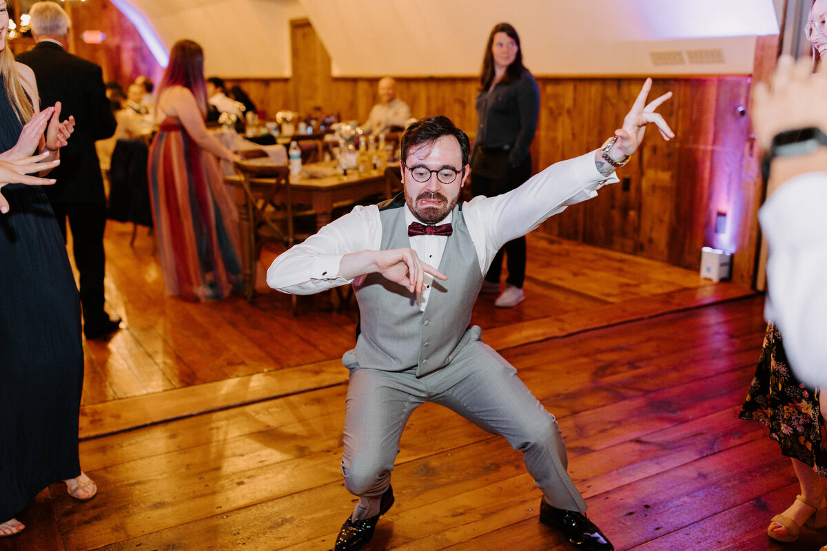 person dancing at a wedding reception with other guests cheering along