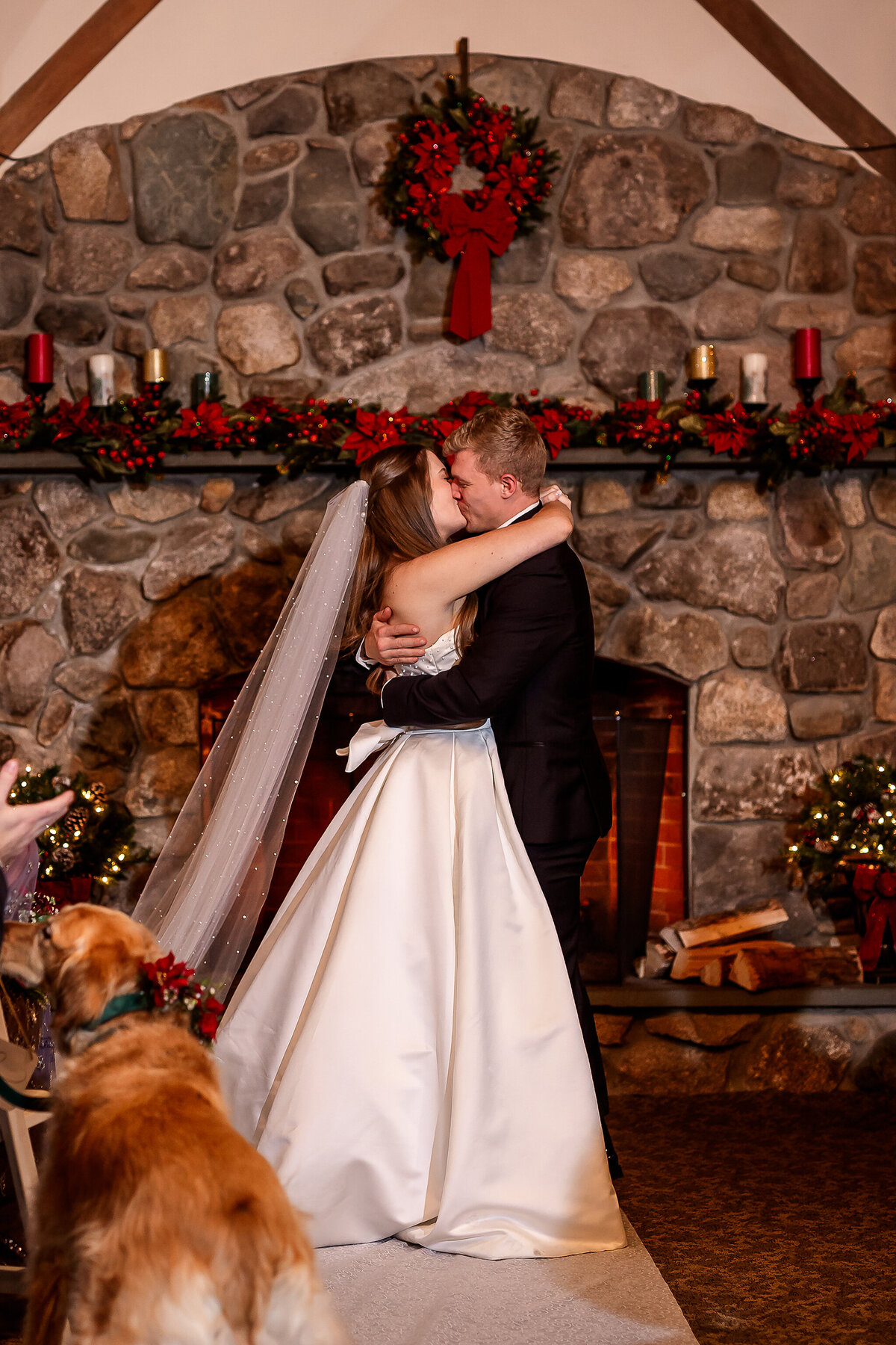 Bride and grooms first kiss in front of fireplace at winter wedding 