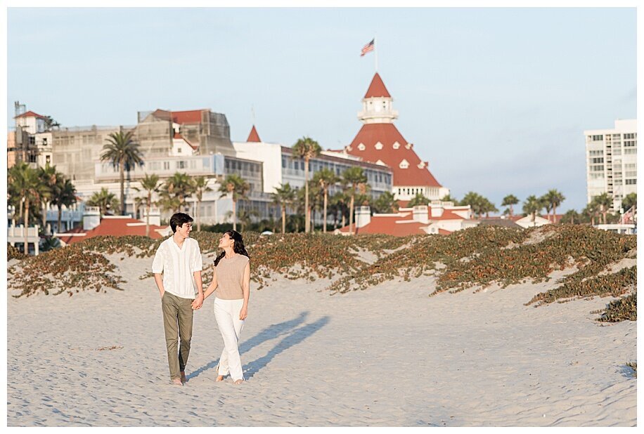 engaged couple walkiing in front of hotel del coronado san diego