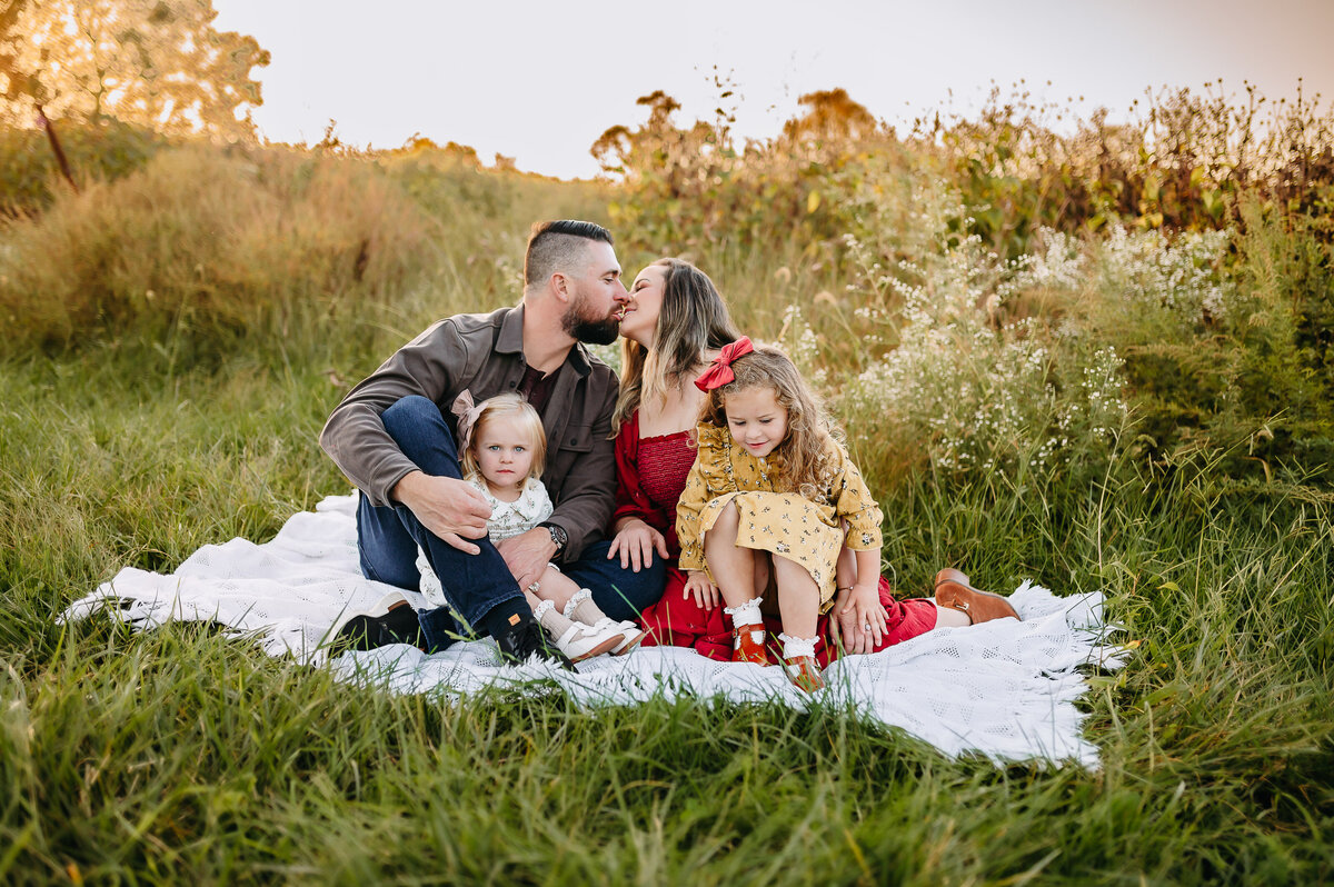 A family is settled on a blanket, cuddling at a vineyard in Davidsonville, MD.