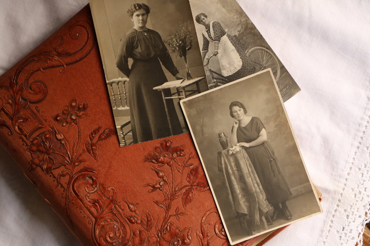 A stack of old wedding photos placed on top of a vintage wedding album, ready for restoration.