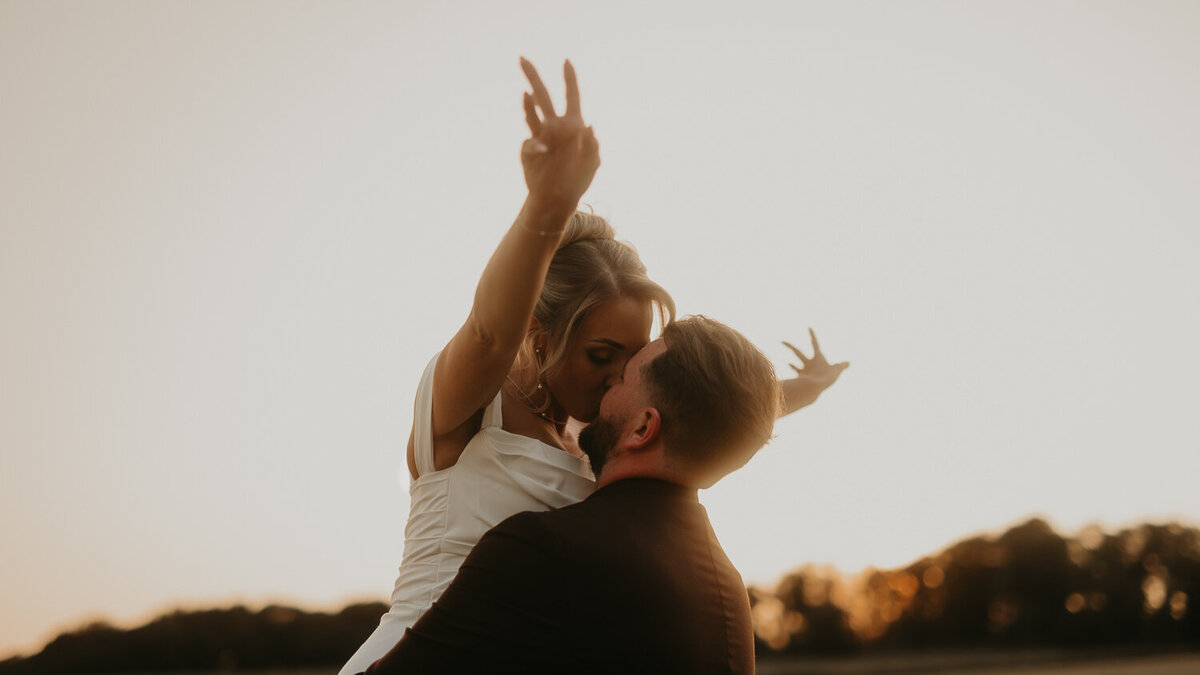 Bride and groom spin around  in the fields at Lapstone Barn during golden hour. 