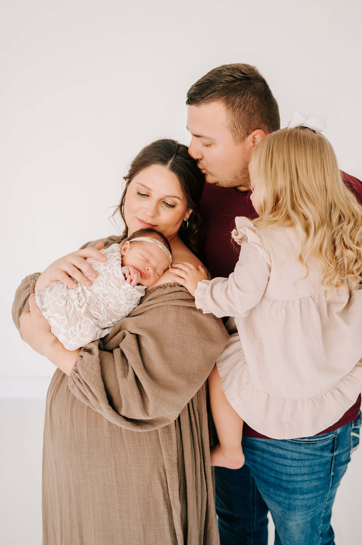 Springfield MO newborn photography of family of 4 cuddling and kissing holding newborn