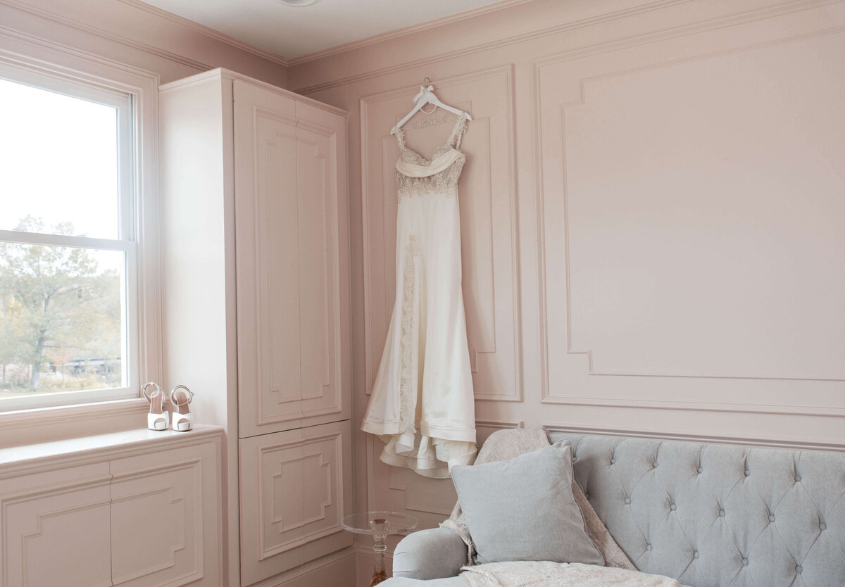 A beautifully draped wedding dress hanging in a modern, elegant setting.