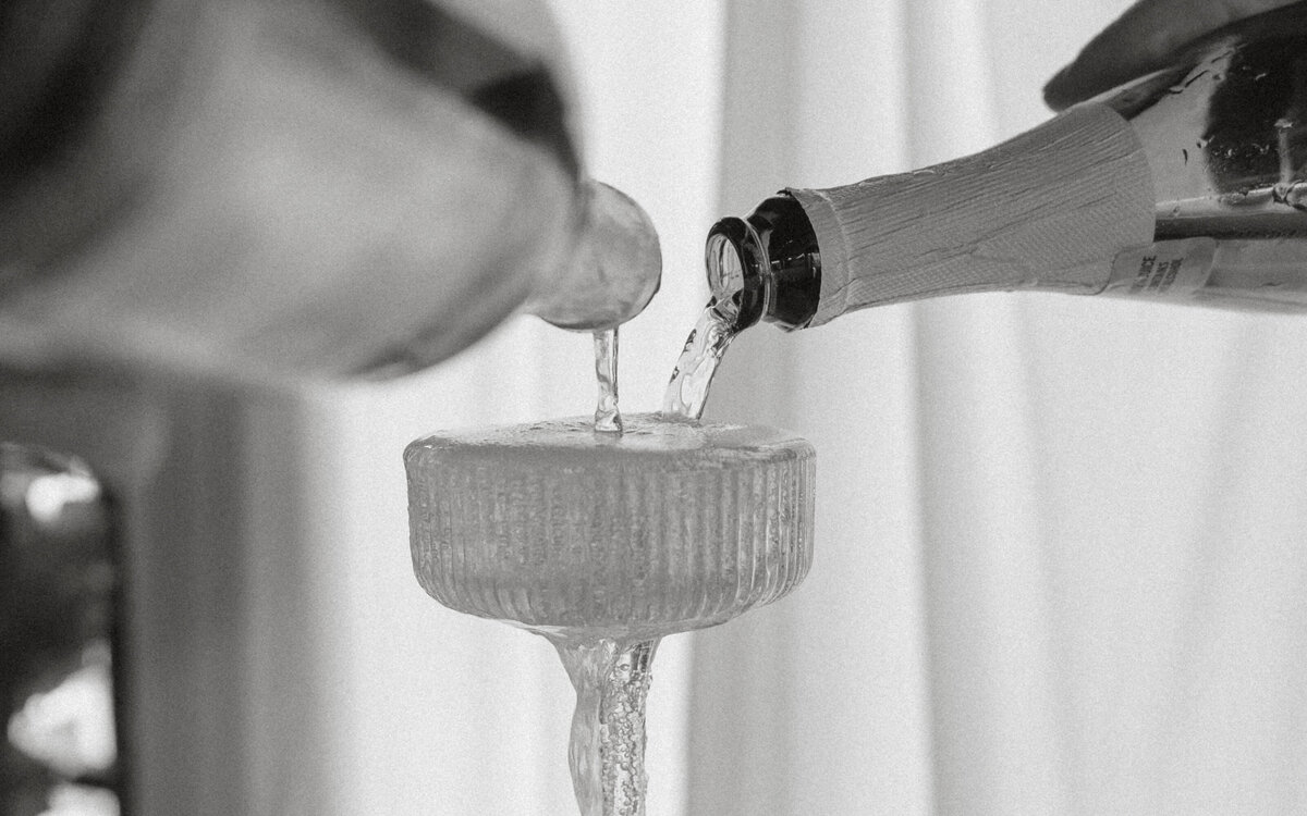 black & white image of champagne being poured into champagne glass close up.