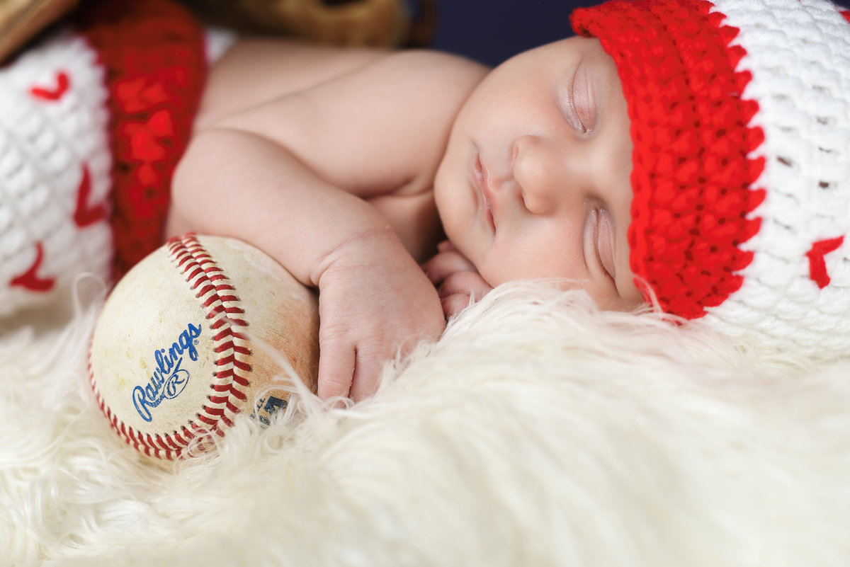 Beautiful Mississippi newborn photography: Baby boy in baseball uniform with Rawlings baseball, baseball newborn session