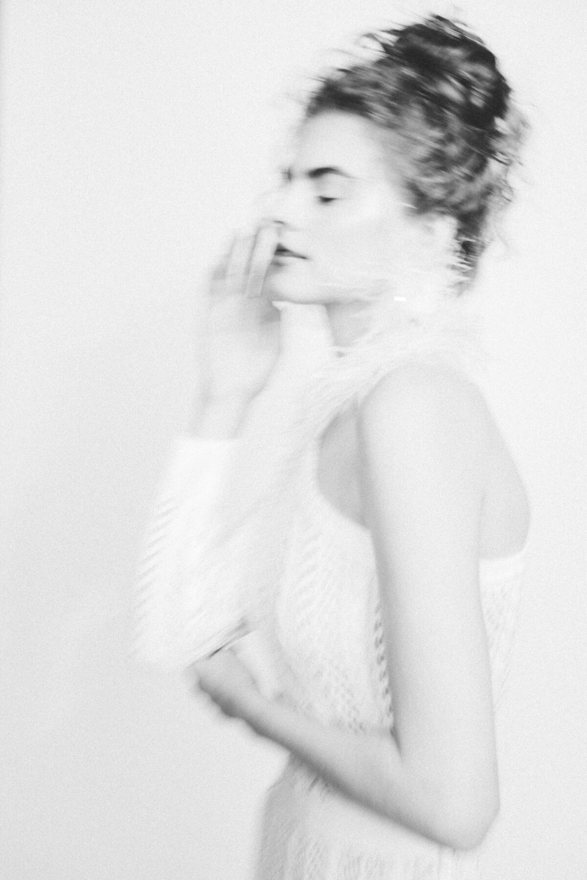 A portrait of a women posing on her side with her eyes close and softly touching her face