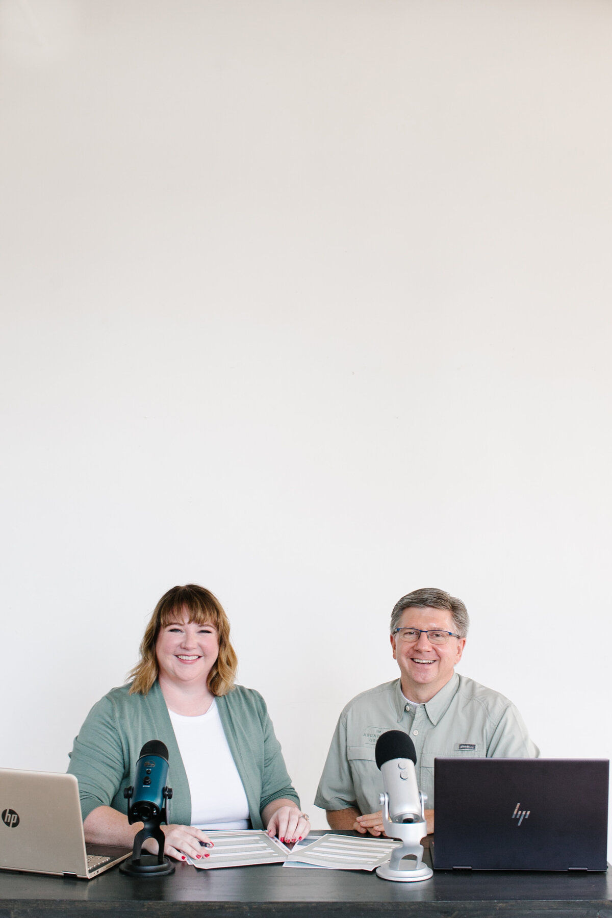 The Abundance Group founders, Ashley Ebert and Dale Henry, smile together behind their desk