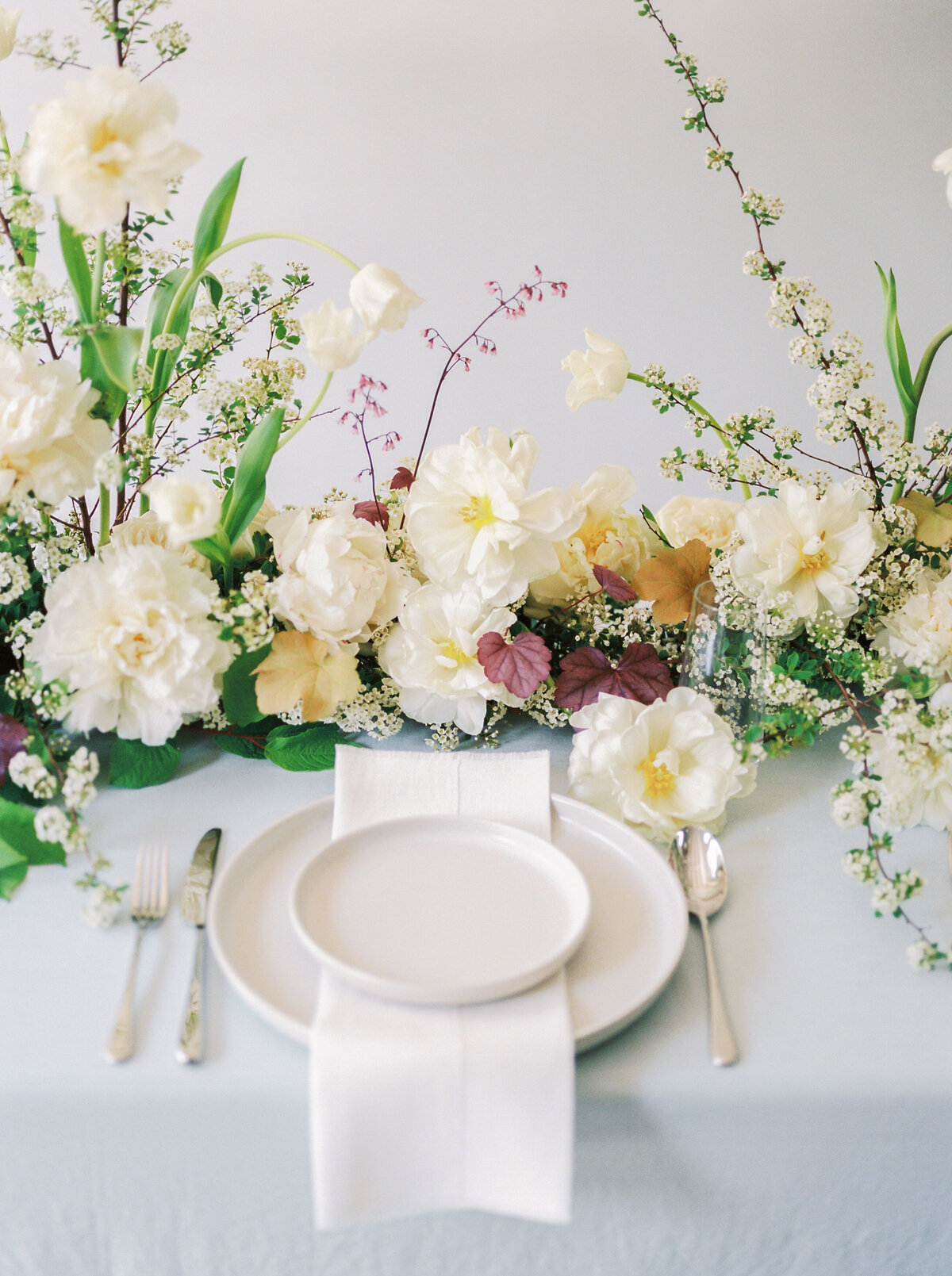 Lush, pastel spring flowers form a long, low table centrepiece at a Montreal wedding.