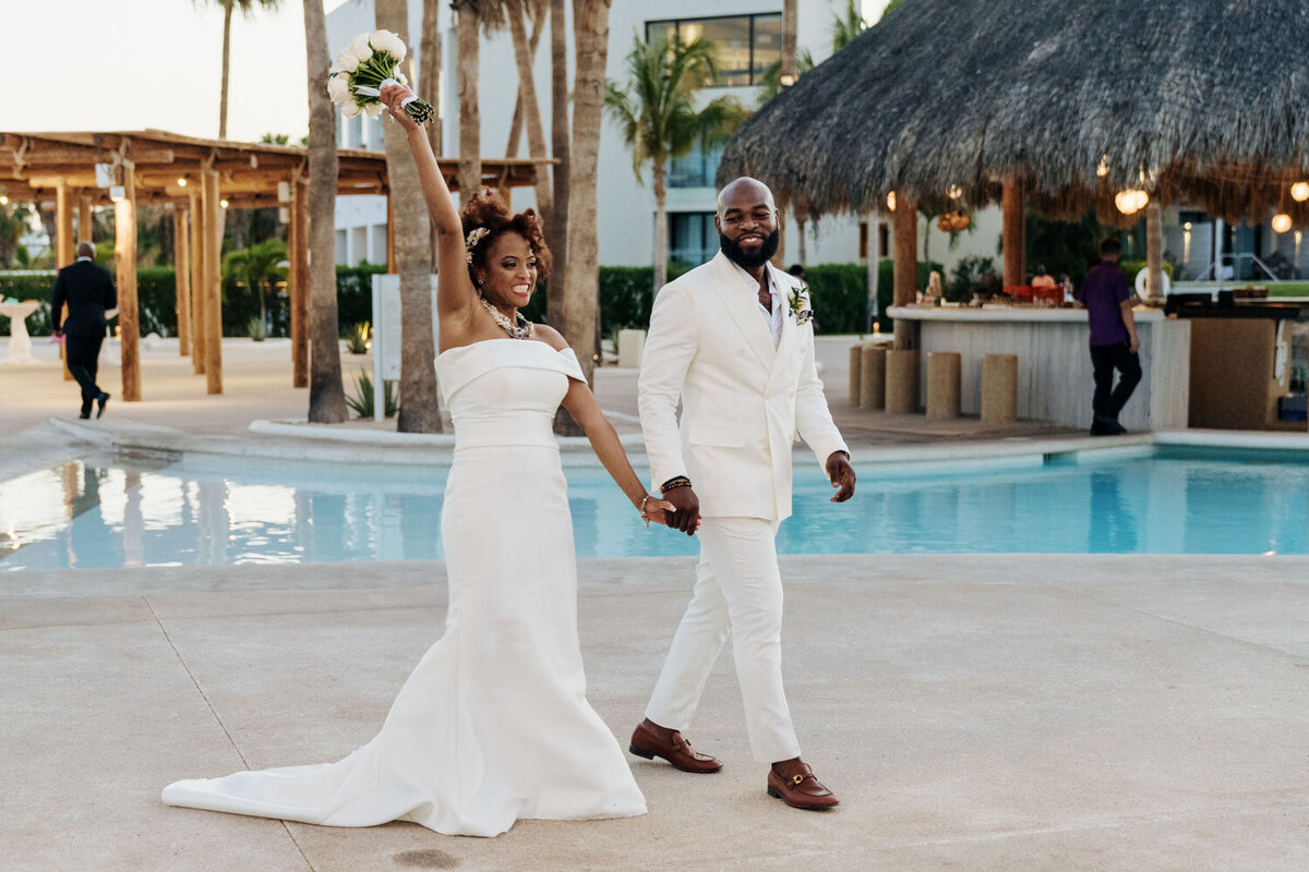 Bride and groom dancing joyfully by a poolside venue