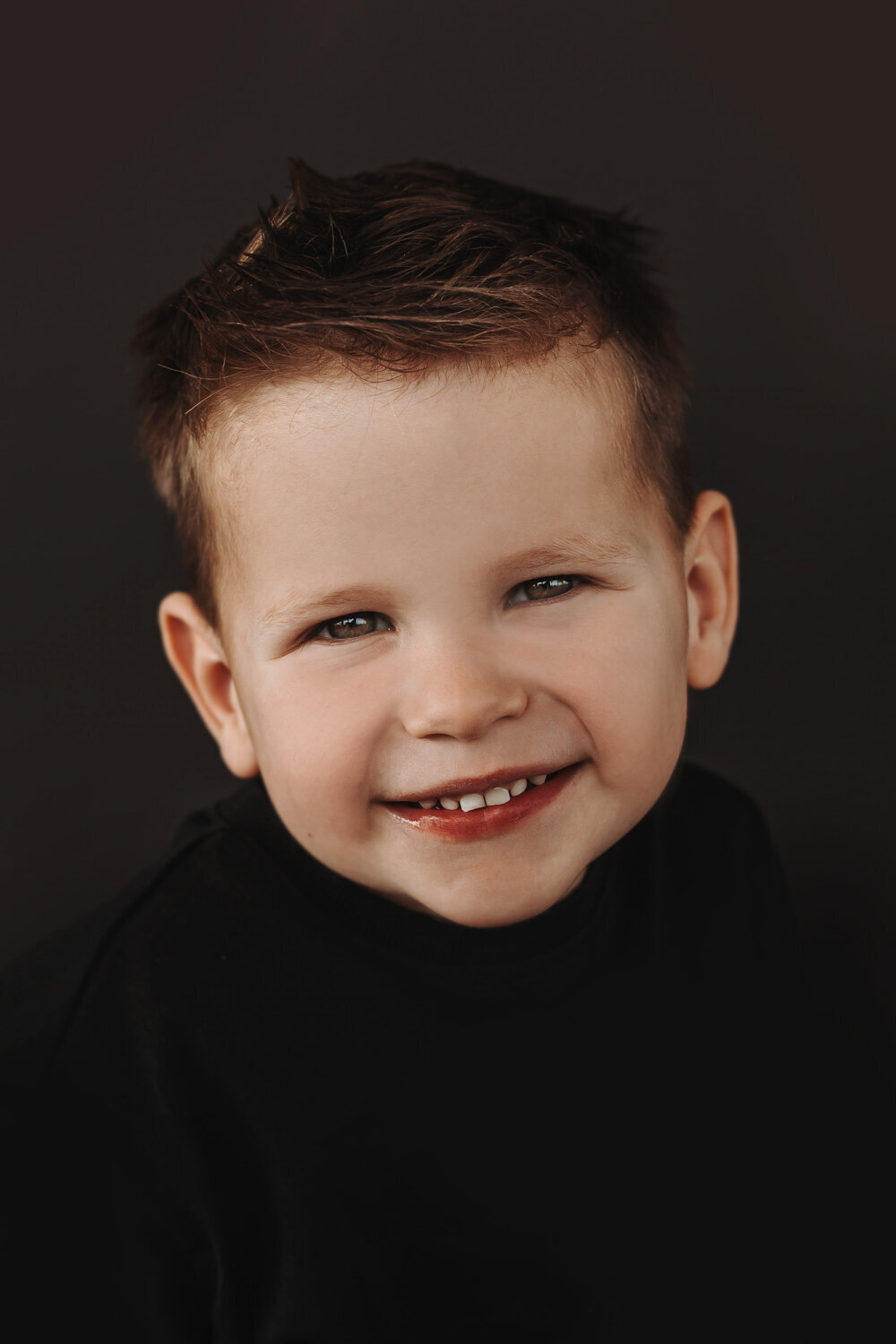 Portret lachende jongen op donkere achtergrond