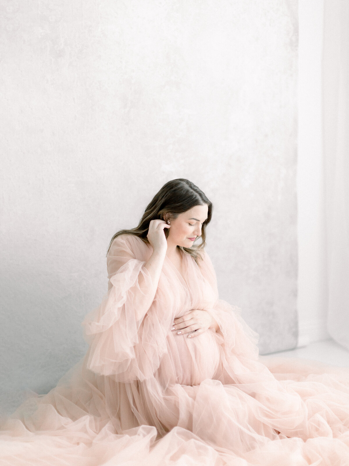 A maternity portrait of a mother in a tulle gown