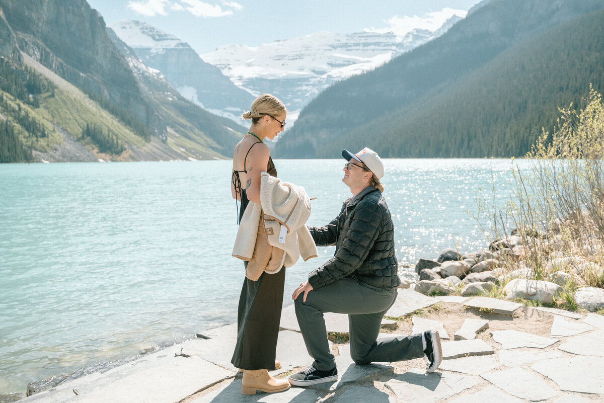 Proposal on stone platform at Lake Louise with dramatic lake and glacier view.
