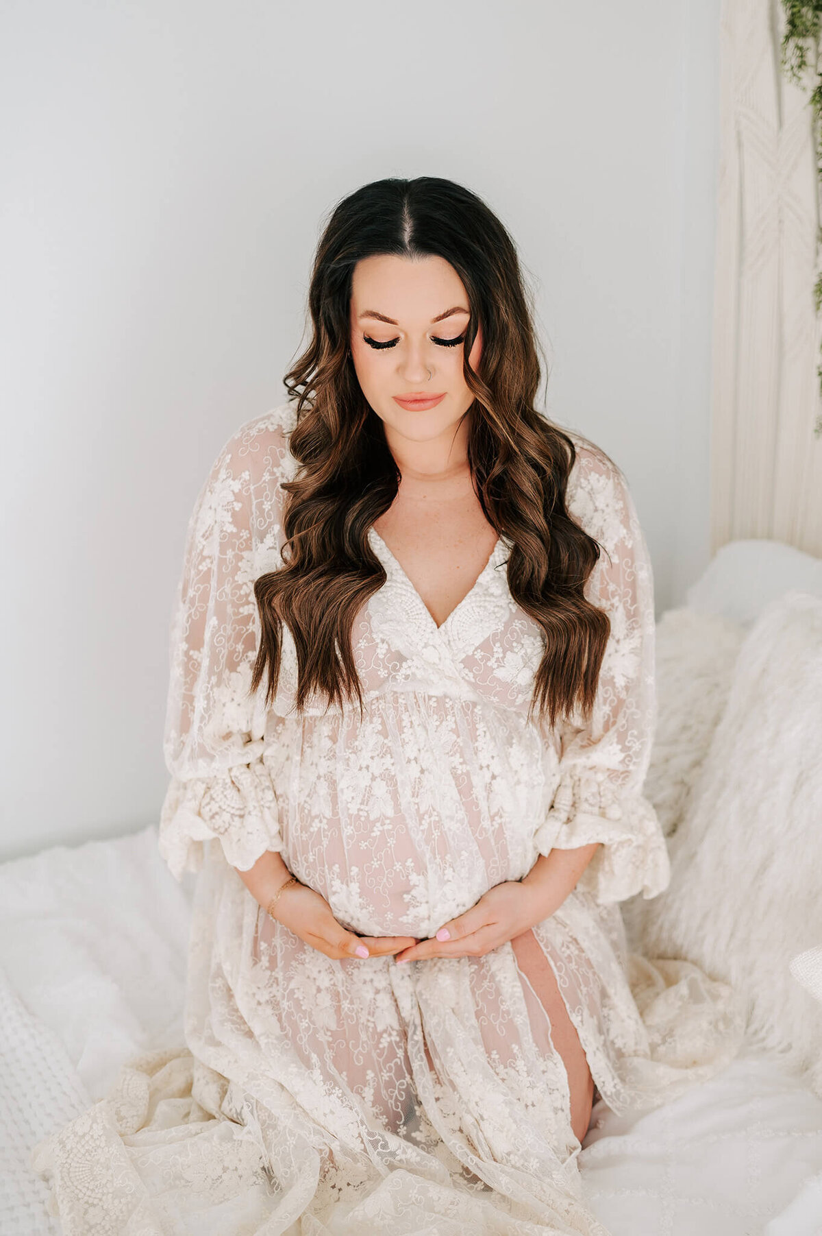 Springfield MO maternity photographer Jessica Kennedy of The XO Photography captures pregnant mom kneeling on the bed looking at her baby bump