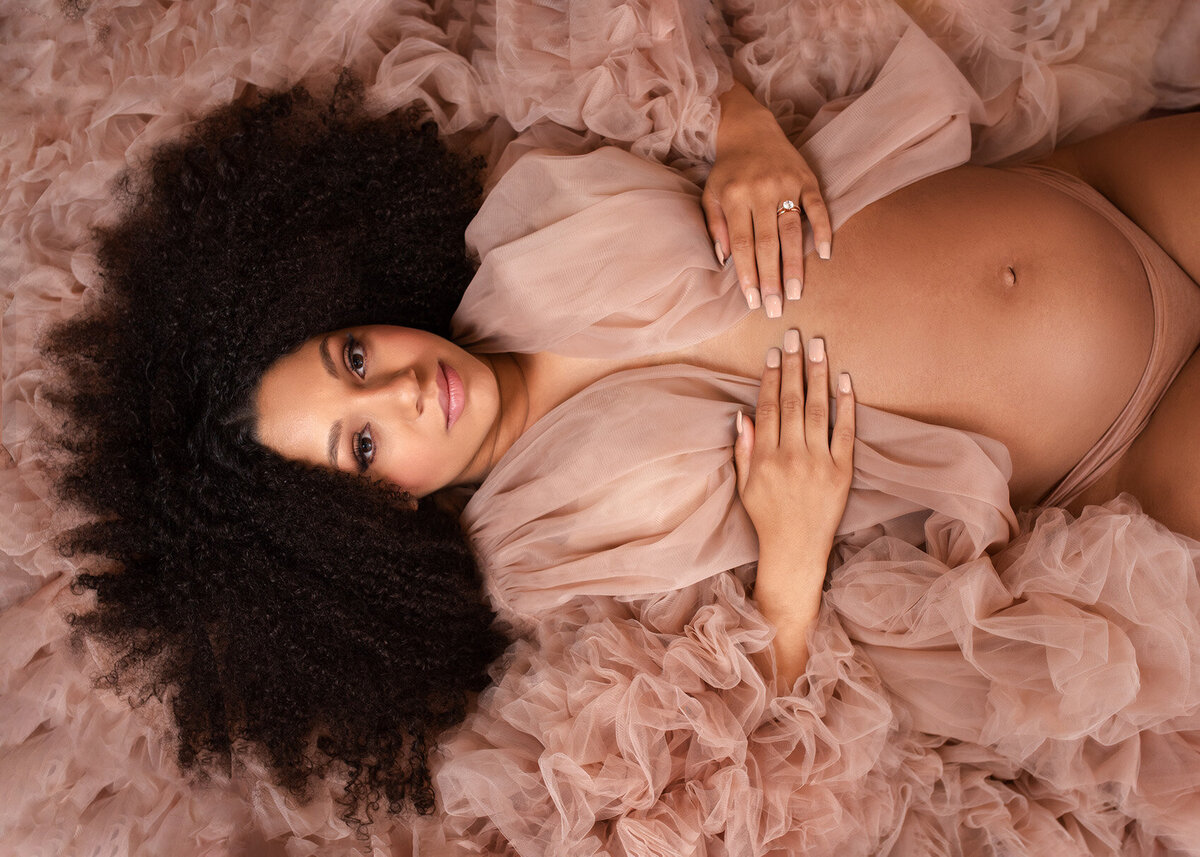 Maternity portrait of a pregnant woman lying down in a couture gown, with ruffles all around her. Captured by Houston maternity photographer Laura King Photography.