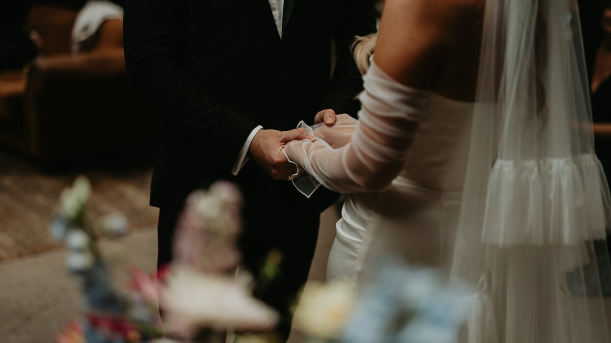 Detail shot of a bride and groom holding hands at their wedding at The Shack Revolution. 