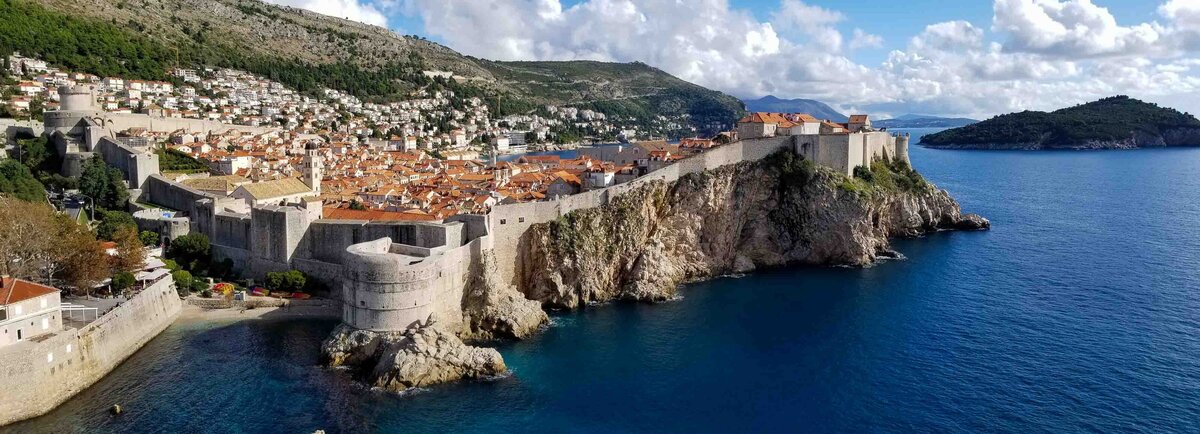 Medieval stone walls surrounding the terracotta rooftops of Dubrovnik’s Old Town, perched on cliffs above the Adriatic Sea in Croatia ©Stephanie Dosch | theViatrix Luxury Travel