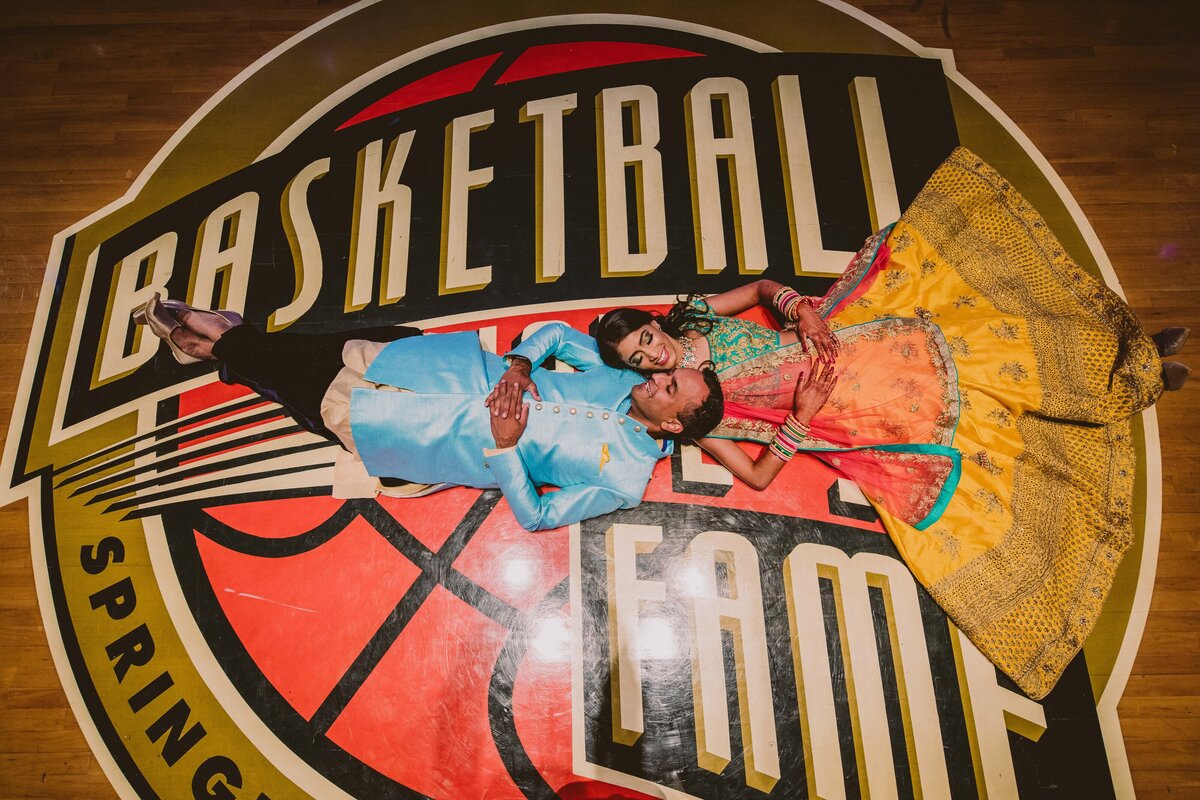 An indian bride and groom laying on the floor at the naismith memorial basketball hall of fame in Massachusetts 