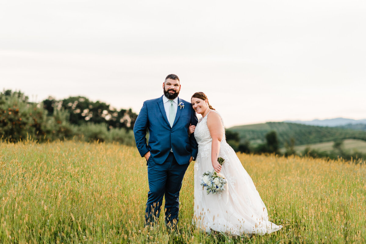 bride and groom posing in a pasture in teh spring at showalter's orchard for their Shenandoah wedding