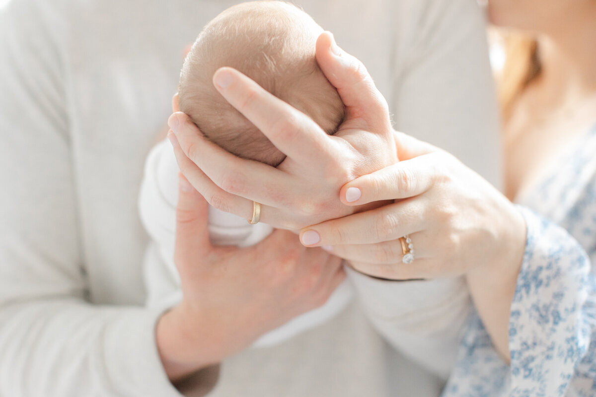 image taken by boston newborn photographer showing close up of new mom and dads hand holding baby