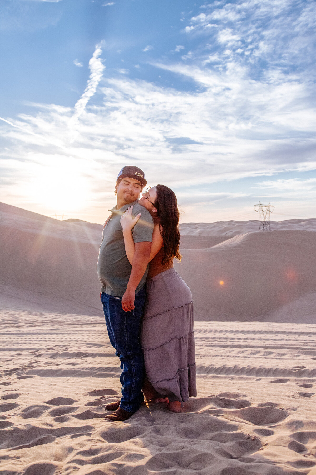 engaged couple embrace in yuma sand dunes