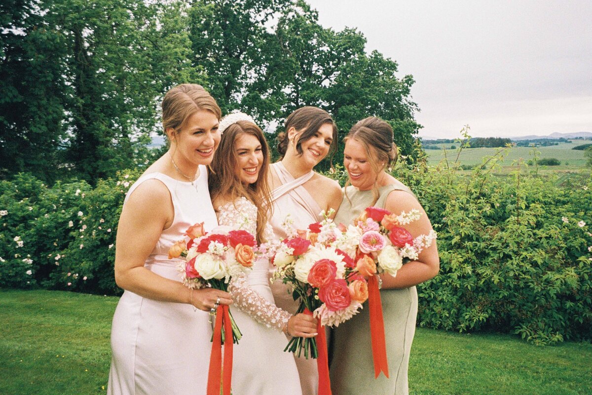 A bride is photographed with her bridal party in 35mm film. They cuddle up and smile candidly.