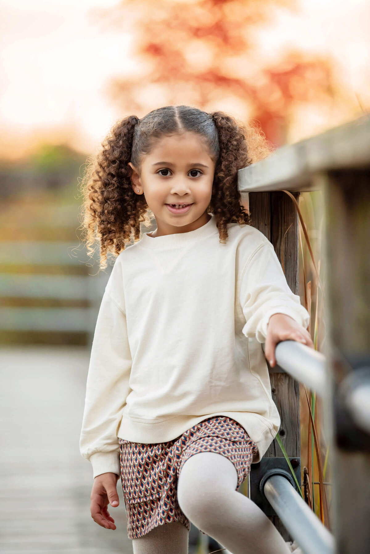 little girl leaning against a bridge for her fall family photos in Burlington, On
