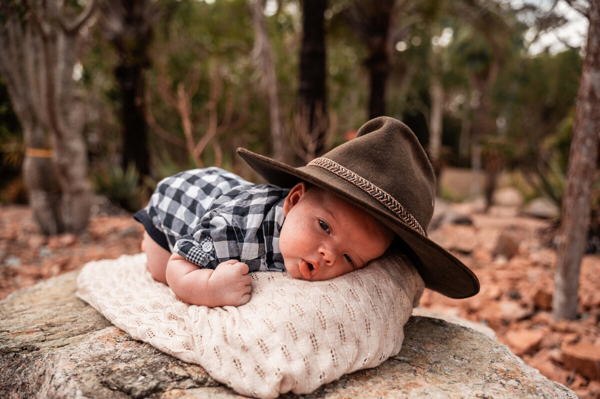 baby boy lying on blanket in a cactus garden wearing a cowboy hat - Townsville Child Milestone Photography by Jamie Simmons