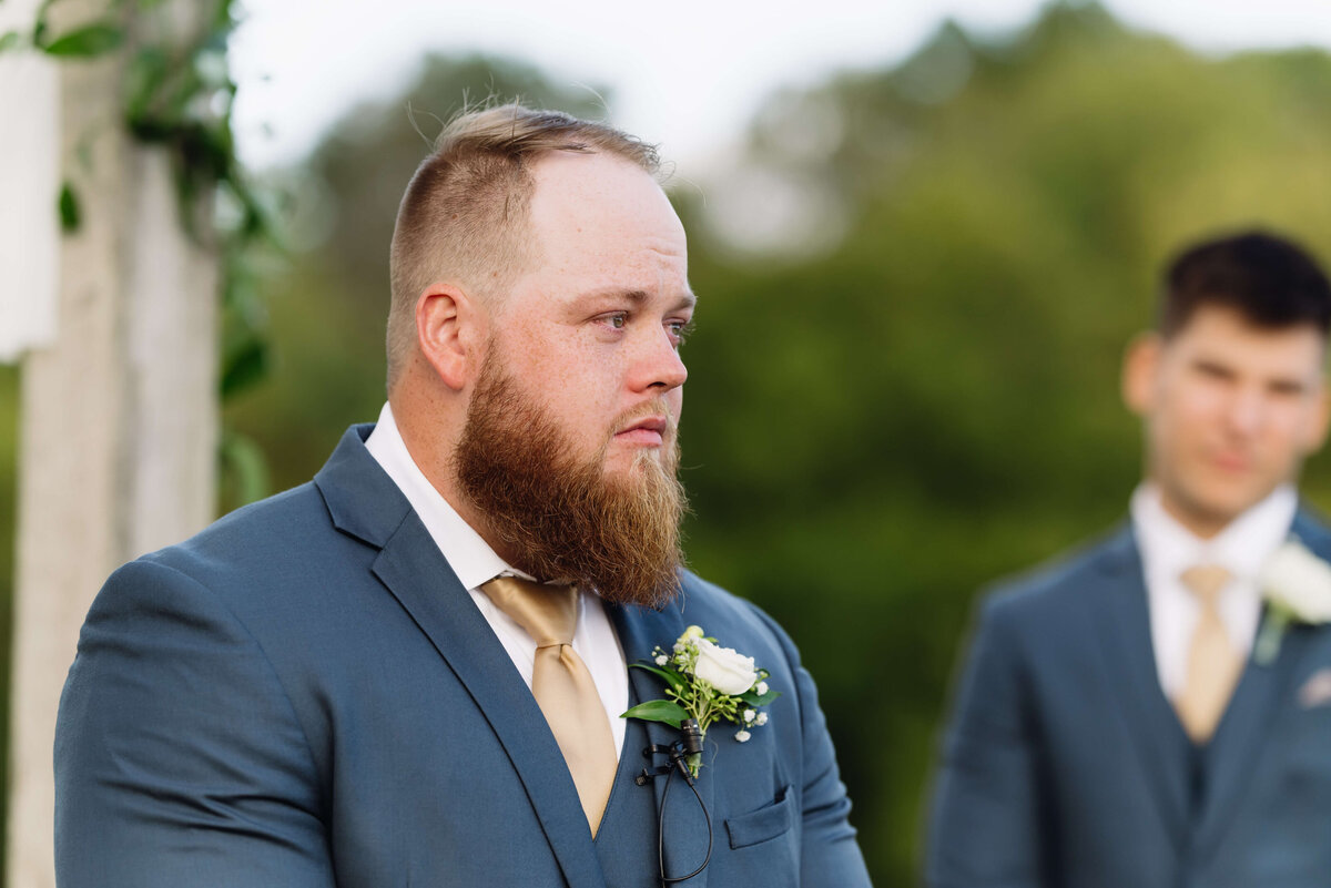 groom sees his bride enter the ceremony space at he end of the aisle while his groomsmen stand behind him