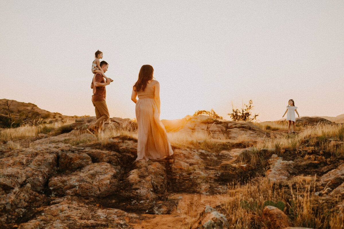A family of four walking on a rocky hill at sunset in the Wichita Mountains of Oklahoma