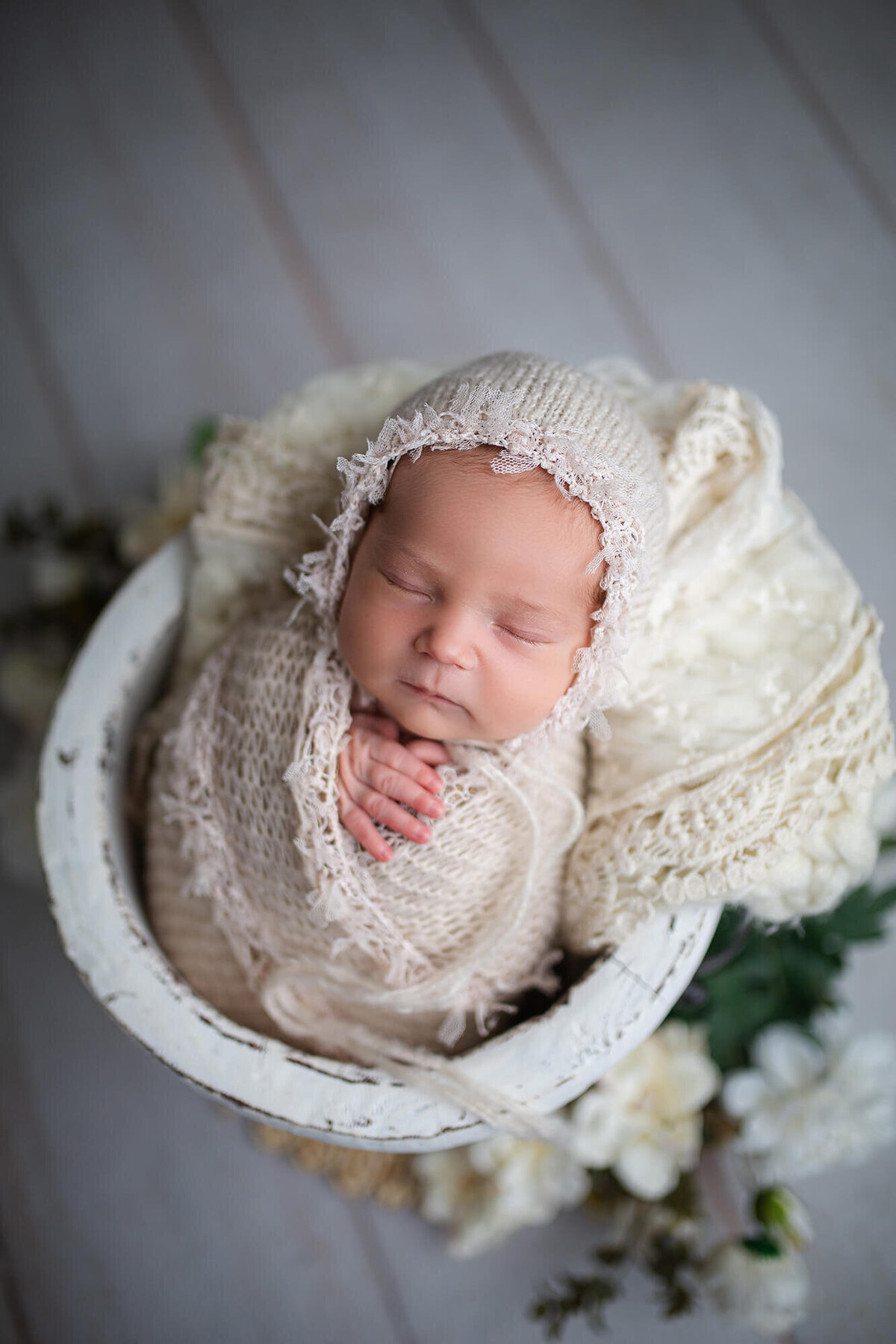 Boho inspired neutral colors with baby wrapped in lace fabrics and wearing a lace bonnet 