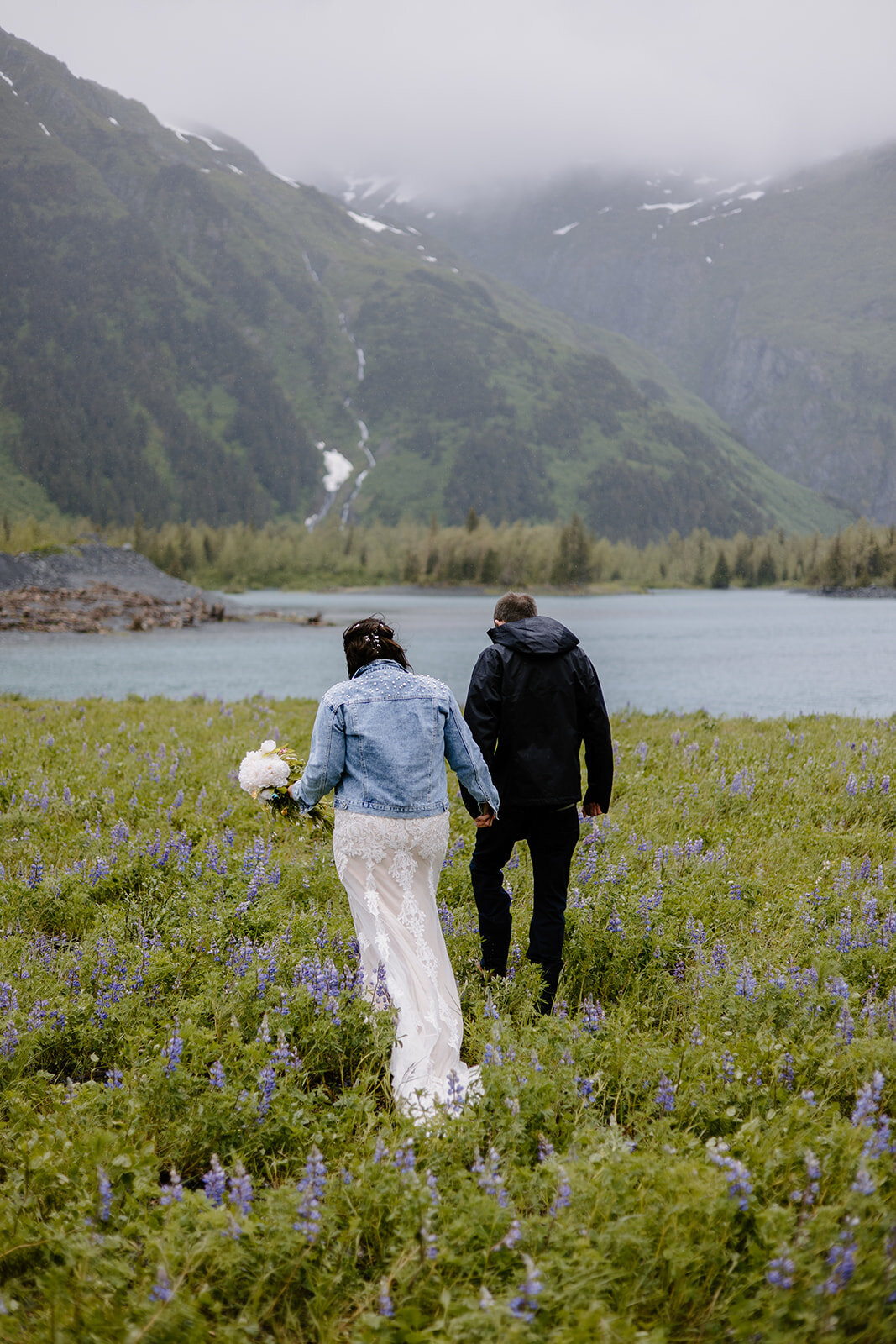 Alaska elopement couple walking towards lake.